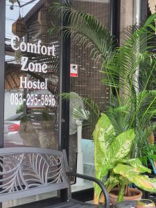 ein Schild an der Tür eines Hotels mit Pflanzen in der Unterkunft Comfort Zone Hostel @ Tha Pae in Chiang Mai