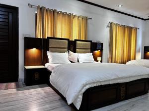 デヘラードゥーンにあるKings Villa 77 Home Stay Dehradunのベッドルーム1室(大型ベッド2台、黄色いカーテン付)