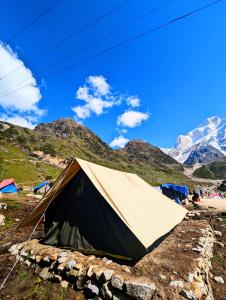 ein Zelt auf einem Feld mit Bergen im Hintergrund in der Unterkunft Kedar Tent House in Kedārnāth