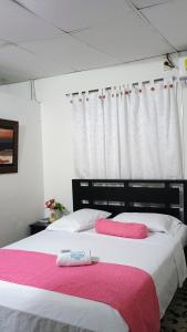 ChigorodóにあるHotel Acuariosのベッドルーム1室(ピンクと白のシーツが備わるベッド2台付) +7枚の写真