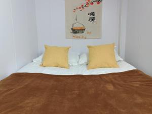 a white bed with two pillows and a picture on the wall at Shanghai Garden Apartment - Near Downtown Wukang Road in Shanghai