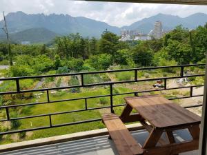 a wooden table and bench on a balcony with mountains at Gilson Guesthouse in Sokcho
