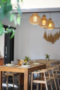 Un comedor con mesas y sillas de madera y luces. en Tattva Uluwatu, Surf & Yoga Retreat, en Jimbaran