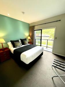 um quarto com uma cama grande e uma varanda em Portside Hotel Gisborne em Gisborne