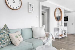 a living room with a blue couch and a clock on the wall at Villa Amaroo in Nelson Bay