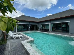 a swimming pool with a chair and a house at Sun Ray Private Pool villa 3 bed in Ao Nang 