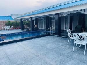 eine Terrasse mit einem Tisch und Stühlen neben einem Pool in der Unterkunft Mayfair Palm Beach Resort in Gopalpur
