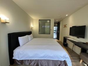 Dormitorio con cama, escritorio y TV en CHECK inn Express Taichung Fuxing en Taichung