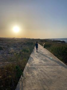 a person walking down a path near the ocean at Pembroke Suites in Pembroke  +11 photos