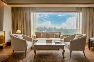 a living room with a couch and chairs and a large window at THE SHILLONG ADDRESS in Shillong