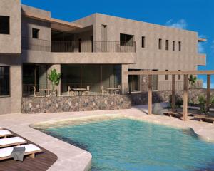 a house with a swimming pool in front of a building at Ammos Eco Residence in Karteros