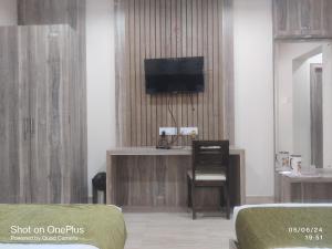 una camera con TV, sedia e letto di Hotel Praj Paradise a Brahmapur
