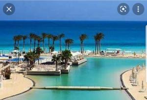 a picture of a beach with palm trees and water at Hacienda bay in El Alamein