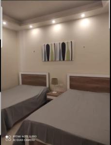 a bedroom with two beds and a painting on the wall at Hacienda bay in El Alamein