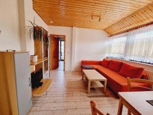 a living room with a red couch and a table at Pension & Wirtshaus ''Tun Eikkoter'' Eichkater in Wieck