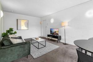 een woonkamer met een bank en een tv bij Sublime 1-Bed Apartment by Royal Park in Melbourne