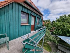a green house with a bench on a deck at Pension & Wirtshaus ''Tun Eikkoter'' Eichkater in Wieck