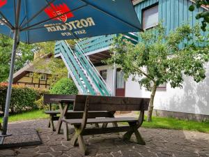 a wooden bench sitting under an umbrella next to a building at Pension & Wirtshaus ''Tun Eikkoter'' Eichkater in Wieck +2 photos
