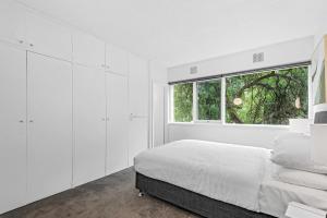 een witte slaapkamer met een bed en een raam bij Sublime 1-Bed Apartment by Royal Park in Melbourne