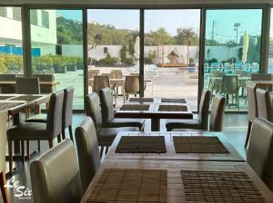 a restaurant with tables and chairs and a large window at Le Six Hotel And Resort in Batroûn
