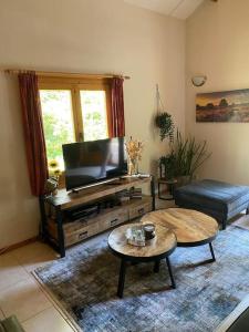 a living room with a flat screen tv and a table at Vakantiehuis midden in het bos vlakbij de Efteling Natuurhuisje Loonse en Drunense duinen in Helvoirt