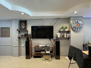 a living room with a television and a clock on the wall at JS786 Cafe&Bistro in Pattaya
