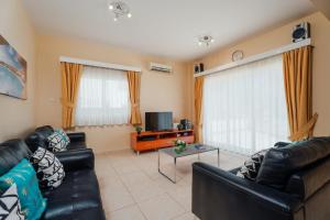 a living room with two leather couches and a tv at Villa Maria in Protaras