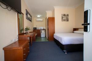 a hotel room with a bedroom with a bed and a desk at Manjimup Motor Inn in Manjimup