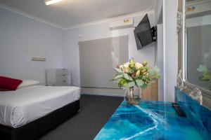 a bedroom with a bed and a vase with flowers in it at Manjimup Motor Inn in Manjimup