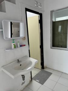 een badkamer met een witte wastafel en een spiegel bij JS786 Hostel in Pattaya