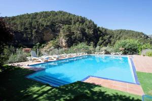 a swimming pool with chairs and a mountain in the background at Finca la Noguera-Sierra Cazorla in Quesada