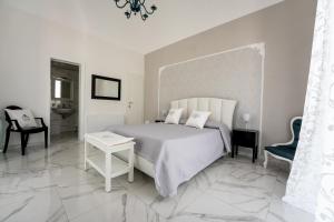 a white bedroom with a bed and a chair at SWEET HOME DELUXe in Rosolini