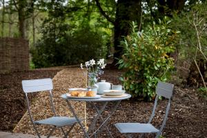 a table with a plate of food and two chairs at Fallow Shepherds Hut Chatsworth Estate in Baslow +1 photo