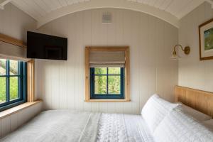 a white bedroom with a bed and a television at Stag Shepherds HutChatsworth Estate in Baslow