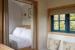 a mirror in a bedroom with a bed and a window at Stag Shepherds HutChatsworth Estate in Baslow +5 photos