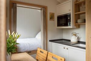 a small kitchen with a bed and a counter top at Mr McGregor’s Garden Shepherds Hut Chatsworth in Baslow