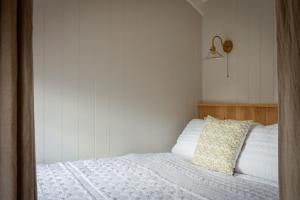 a bedroom with a bed with white sheets and a pillow at Mr McGregor’s Garden Shepherds Hut Chatsworth in Baslow +2 photos