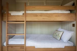 two bunk beds in a room with a white bed at Mr McGregor’s Garden Shepherds Hut Chatsworth in Baslow