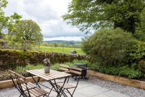 a picnic table and a grill in a garden at Mr McGregor’s Garden Shepherds Hut Chatsworth in Baslow