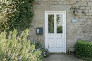 a white door on the side of a brick building at Keepers CottageChatsworth Estate in Baslow