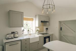 a kitchen with a sink and a window and a door at Keepers CottageChatsworth Estate in Baslow