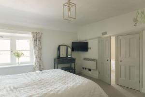 a white bedroom with a bed and a television at Keepers CottageChatsworth Estate in Baslow