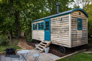a tiny house with a ladder in a yard at Oak Tree Shepherds Hut Chatsworth Estate in Baslow
