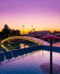 ein Pool mit einer gelben Brücke und einem Sonnenschirm in der Unterkunft Hotel Eiffel in Tirana