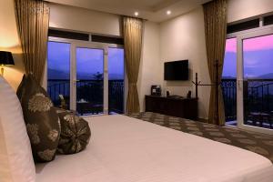 Montrose Golf Resort and Spa - Coorg في Jambur: غرفة نوم مع سرير وبلكونة مع تلفزيون