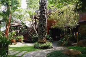 清迈Baansuwanburi - บ้านสุวรรณบุรี的一座房子前面种有棕榈树的花园
