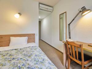a bedroom with a bed and a desk with a lamp at Kumagaya Royal Hotel Suzuki in Kumagaya