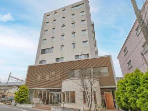 a tall white building with a building at Kumagaya Royal Hotel Suzuki in Kumagaya