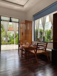 a dining room with a table and chairs and windows at Lightly Homestay in Ho Coc