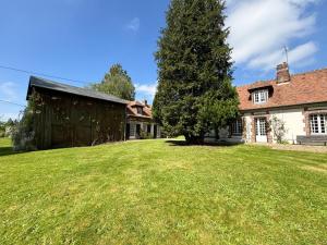 a large yard with a tree in front of a house at La Maison du Tilleul avec Piscine couverte chauffée in Saint-Sulpice-sur-Risle
